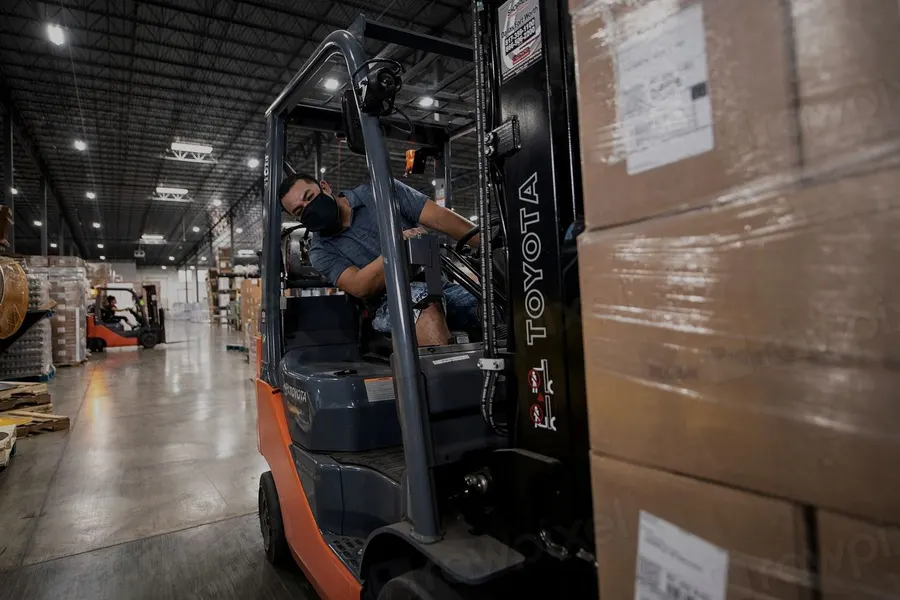 Warehouse operator moving pallets of goods with a forklift